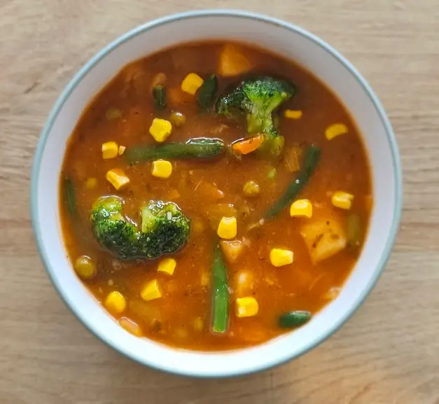A bowl of vegetable soup on a kitchen table